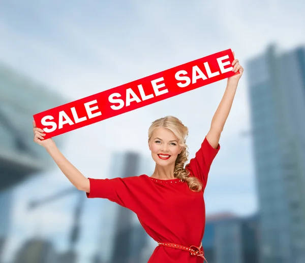 Улыбается женщина в платье с красной Продажа знак — стоковое фото