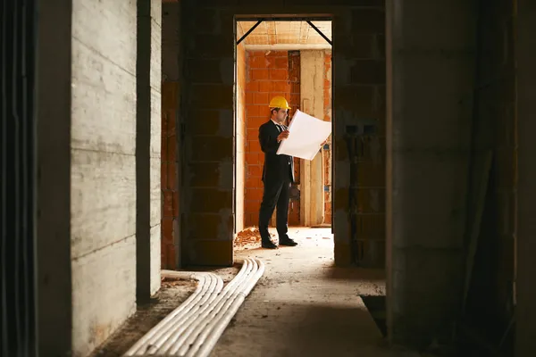 Архитектор стоя в доме под строительство здания пла — стоковое фото